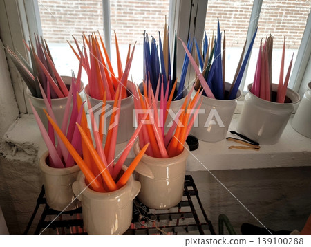 Multicolored long taper candles in ceramic jugs 139100288
