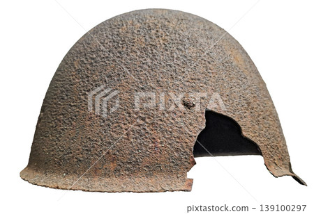 A vintage military helmet displays heavy rust and damage with a large jagged hole. This item is isolated, highlighting its worn condition and historical significance. A vintage military helmet displays heavy rust and damage with a large jagged hole. This item is isolated, highlighting its worn condition and historical significance. 139100297