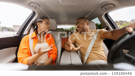 Young African American couple arguing inside car, expressing frustration and disagreement Young African American couple arguing inside car, expressing frustration and disagreement 139100449