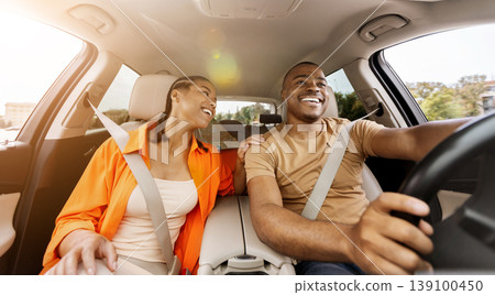 Young African American couple enjoying drive together, smiling in car Young African American couple enjoying drive together, smiling in car 139100450