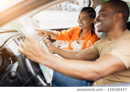 Young African American couple using paper map while sitting inside car Young African American couple using paper map while sitting inside car 139100457