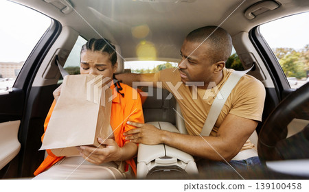 Young black woman feeling sick in a car using a paper bag Young black woman feeling sick in a car using a paper bag 139100458