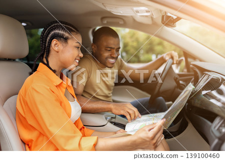 Young Black couple smiling while looking at paper map together in car 139100460
