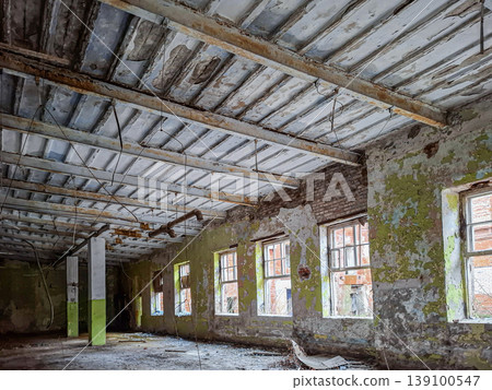 The spacious hall in the tobacco factory shows worn brick walls and a weathered ceiling. Light enters through many broken windows, revealing the factory's history in Yelets. The spacious hall in the tobacco factory shows worn brick walls and a weathered ceiling. Light enters through many broken windows, revealing the factory's history in Yelets. 139100547