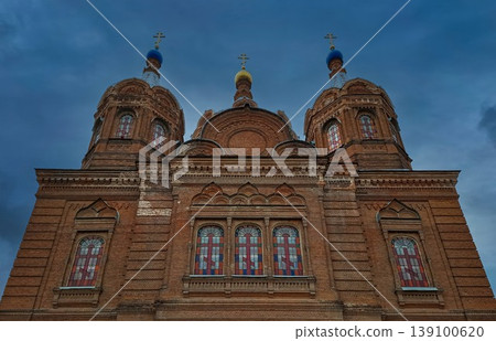 The red brick Russian Orthodox Church of the Yelets Icon of the Mother of God taken from a low angle. The church stands tall under a blue sky with clouds. The red brick Russian Orthodox Church of the Yelets Icon of the Mother of God taken from a low angle. The church stands tall under a blue sky with clouds. 139100620