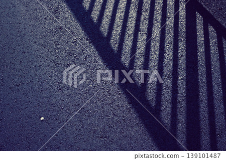 The shadow of a fence on the asphalt The shadow of a fence on the asphalt 139101487