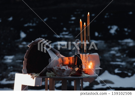 Candlelit Roses On Snowy Outdoor Table, Amber Glow From Tapered Candles Casting Long Shadows Over Scattered Petals, Glassware And Bottle, Creating Intimate Moody Tableau With Reflective, Candlelit Roses On Snowy Outdoor Table, Amber Glow From Tapered Candles Casting Long Shadows Over Scattered Petals, Glassware And Bottle, Creating Intimate Moody Tableau With Reflective, 139102506