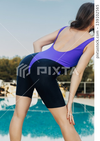 Closeup Poolside White Athlete Showing Unitard Curve And Toned Torso, Purple Panels And Textured Fabric Highlighted By Sun, Focused Fashion And Fitness Detail For Campaigns. 139102565