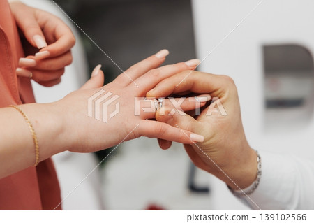 Detailed View Of Band Sliding Over Knuckle. Warm Tones Highlight Personal Moment Of Ring Fitting. Soft Background And Warm Colors Emphasize Intimacy Of Ring Fitting Scene Detailed View Of Band Sliding Over Knuckle. Warm Tones Highlight Personal Moment Of Ring Fitting. Soft Background And Warm Colors Emphasize Intimacy Of Ring Fitting Scene 139102566