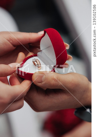 Closeup Hands Holding Red Box, Engagement Ring Revealed, Partner Offering Gold Band During Intimate Proposal, Velvet Texture, Soft Bokeh Background, Warm Lighting, Emotion And Anticipation 139102586