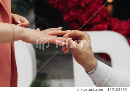 Closeup Of Hands Exchanging Rings. Close Perspective Capturing Intimate Moment Of Ring Placement. Focused Image Showing Hands Exchanging Wedding Bands During Emotional Ceremony 139102593