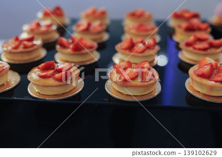 Fresh Strawberry Tartlets On Black Tray, Rows Of Mini Pastries Topped With Sliced Berries And Glossy Glaze, Delicate Cream Filling And Flaky Shells Arranged For Elegant Buffet Presentation, 139102629