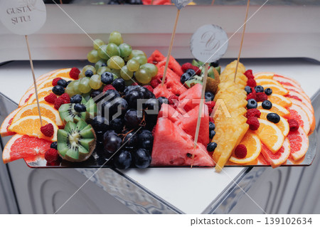 Vivid Fruit Platter. Vibrant Collection Of Fresh Fruit Arranged On White Plate. An Energetic And Colorful Presentation Showcasing Array Of Ripened Fruits On Clean White Surface Vivid Fruit Platter. Vibrant Collection Of Fresh Fruit Arranged On White Plate. An Energetic And Colorful Presentation Showcasing Array Of Ripened Fruits On Clean White Surface 139102634
