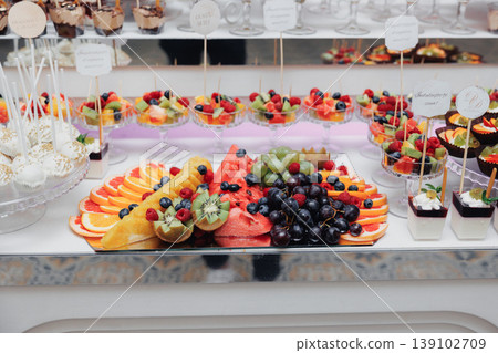 Colorful Fruit Platter And Dessert Display With Sliced Citrus, Berries And Tropical Skewers Arranged On Marble Counter, Bright Summer Vibe For Brunch Or Cocktail Station Colorful Fruit Platter And Dessert Display With Sliced Citrus, Berries And Tropical Skewers Arranged On Marble Counter, Bright Summer Vibe For Brunch Or Cocktail Station 139102709