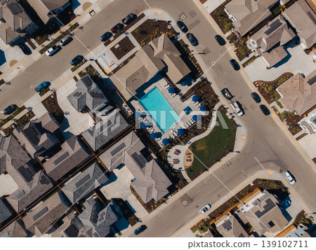 Aerial Community Pool Surrounded Homes Sundrenched Residential Complex With Turquoise Water, Lounge Chairs, Umbrellas, Cars Parked On Driveways, Manicured Lawns, Warm Summer Atmosphere Ideal 139102711