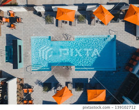 Aerial Rooftop Pool With Orange Umbrellas, Sunlit Turquoise Water, Geometric Tile Deck, Neatly Arranged Lounge Chairs And Parasols, Bold Shadow Patterns, Urban Skyline Glimpses, Curated Aerial Rooftop Pool With Orange Umbrellas, Sunlit Turquoise Water, Geometric Tile Deck, Neatly Arranged Lounge Chairs And Parasols, Bold Shadow Patterns, Urban Skyline Glimpses, Curated 139102712