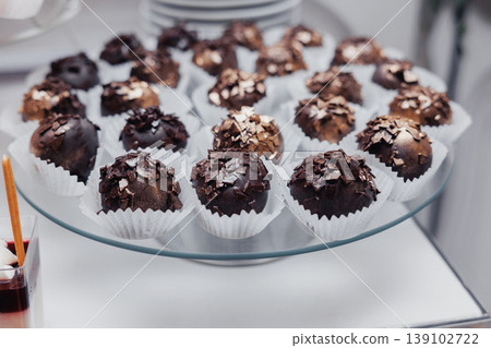 Dark Chocolate Truffles On Glass Plate, Rich Cocoa Clusters Topped With White Sprinkles In Paper Cups, Decadent Texture And Glossy Finish, Handmade Confections Ideal For Dessert Buffet 139102722