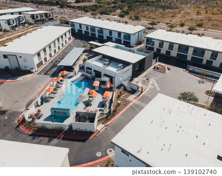 Pool Scene Overview. High Angle Perspective Of Leisure Pool Surrounded By Apartments. Overhead Shot Showcasing Glamorous Poolside Setting With Colorful Inflatables And Umbrellas Pool Scene Overview. High Angle Perspective Of Leisure Pool Surrounded By Apartments. Overhead Shot Showcasing Glamorous Poolside Setting With Colorful Inflatables And Umbrellas 139102740
