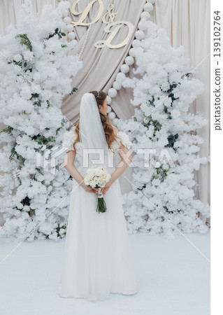 Bride In White Gown, Snowy Arch, Caucasian Bride Standing Holding Ivory Bouquet, Veil Draped Over Shoulders, Frosted Evergreen Backdrop, Soft Natural Light, Elegant Drapery With Gold Bride In White Gown, Snowy Arch, Caucasian Bride Standing Holding Ivory Bouquet, Veil Draped Over Shoulders, Frosted Evergreen Backdrop, Soft Natural Light, Elegant Drapery With Gold 139102764