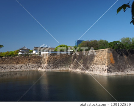 The Otemon Gate and Tamon-yagura Tower of Osaka Castle stand out against the blue sky, a scene of the outer moat in early summer. 139102839