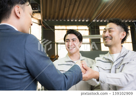 畫面描繪了推銷員和工廠工人握手之間的信任，象徵著商業合同，暗示著夥伴關係、合作和融資。 139102909