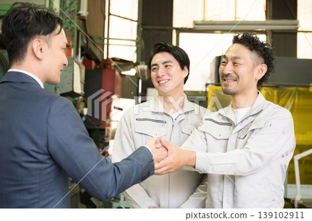 畫面描繪了推銷員和工廠工人握手之間的信任，象徵著商業合同，暗示著夥伴關係、合作和融資。 139102911