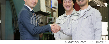 A scene depicting the trust between a salesman and a worker shaking hands in a manufacturing plant; a business contract or agreement scene; business partnership, cooperation, loan, etc. A scene depicting the trust between a salesman and a worker shaking hands in a manufacturing plant; a business contract or agreement scene; business partnership, cooperation, loan, etc. 139102913