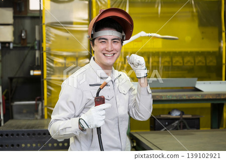 A worker wearing a welding mask; a craftsman at a manufacturing site; a welder and other skilled workers; a job change and recruitment image; a safety pose. A worker wearing a welding mask; a craftsman at a manufacturing site; a welder and other skilled workers; a job change and recruitment image; a safety pose. 139102921