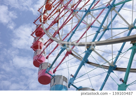 A close-up of a Ferris wheel at an amusement park with a blue sky in the background. A close-up of a Ferris wheel at an amusement park with a blue sky in the background. 139103487