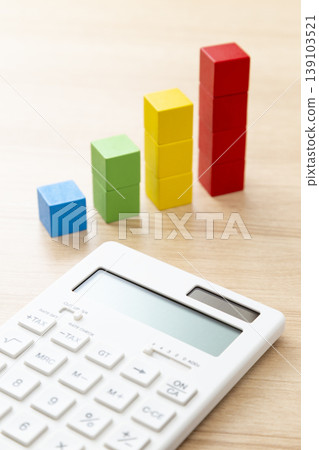 A calculator and a building block graph on a desk 139103521