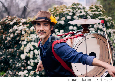 Adult man with a mustache, dressed formally and colorfully, posing and playing a bass drum on his back, Chilean chinchinero, street musician who plays the bass drum and dances in the streets Adult man with a mustache, dressed formally and colorfully, posing and playing a bass drum on his back, Chilean chinchinero, street musician who plays the bass drum and dances in the streets 139104782