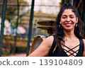 Beautiful Chilean Latina woman smiling with attitude, with her drum and cymbals on her back, detail of her musical instrument, female percussionist, street musician, dancing and playing her drum  139104809