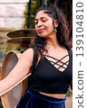 Beautiful Chilean Latina woman smiling with attitude, with her drum and cymbals on her back, detail of her musical instrument, female percussionist, street musician, dancing and playing her drum  139104810