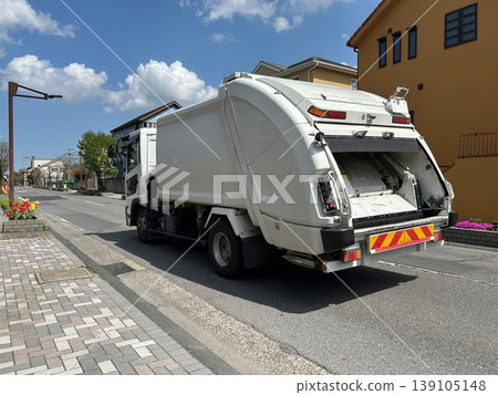 A garbage truck in motion. 139105148
