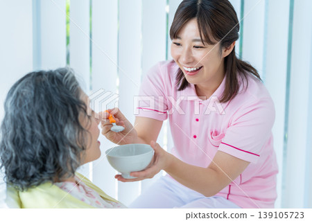 老婦人在床上和護理人員一起吃飯 老婦人在床上和護理人員一起吃飯 139105723