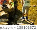 Playing in the river by pouring water 139106672