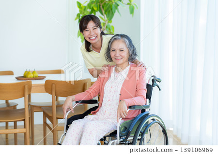 Caregiver supporting a woman in a wheelchair Caregiver supporting a woman in a wheelchair 139106969