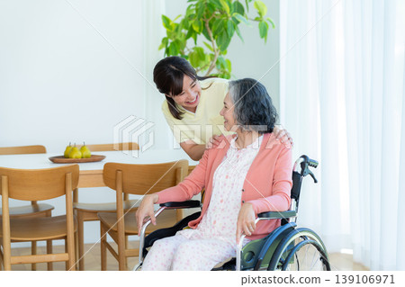 Caregiver supporting a woman in a wheelchair Caregiver supporting a woman in a wheelchair 139106971