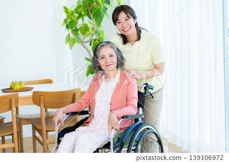 Caregiver supporting a woman in a wheelchair Caregiver supporting a woman in a wheelchair 139106972