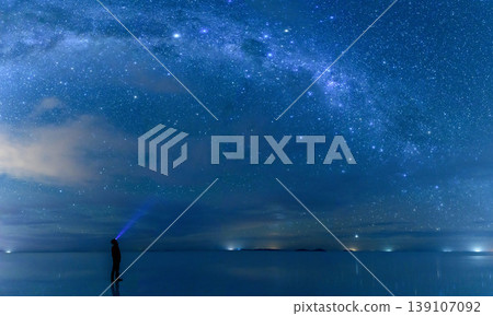 Serene person watches milky way night sky over uyuni salt flat in bolivia with reflection Serene person watches milky way night sky over uyuni salt flat in bolivia with reflection 139107092