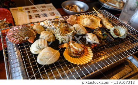 Enjoy fresh seafood grilled over a charcoal fire, including scallops and turban shells. Enjoy fresh seafood grilled over a charcoal fire, including scallops and turban shells. 139107318