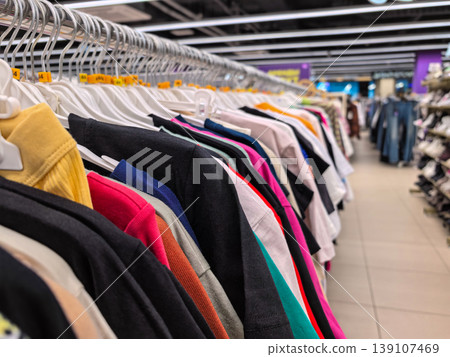Row of Colorful Clothes Hanging on Racks in a Retail Store Fashion Boutique Row of Colorful Clothes Hanging on Racks in a Retail Store Fashion Boutique 139107469