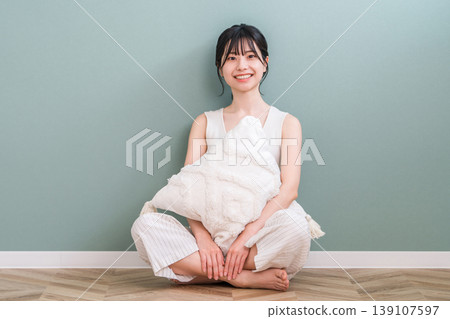 Smiling young Asian woman relaxing while hugging a cushion in the living room at home 139107597