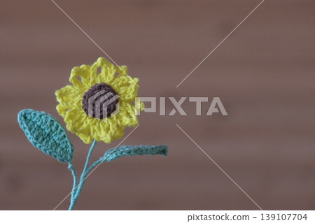Close-up of knitted sunflowers against a wood panel background Close-up of knitted sunflowers against a wood panel background 139107704
