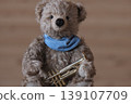 A teddy bear holding a trumpet, with a little space left on the right. 139107709