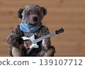 A teddy bear holding a guitar; dark brown bear; brown guitar; space on the right. 139107712