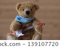 A teddy bear holding a guitar; yellow bear, red guitar; a close-up shot. 139107720