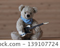 A teddy bear holding a guitar; beige bear, beige guitar 139107724