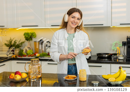 Middle-aged woman dancing to music while making healthy fresh breakfast toast in own kitchen indoors Middle-aged woman dancing to music while making healthy fresh breakfast toast in own kitchen indoors 139108129