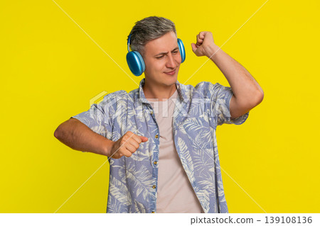 Adult man dancing in wireless headphones enjoying music with positive emotion happy listening vibe Adult man dancing in wireless headphones enjoying music with positive emotion happy listening vibe 139108136